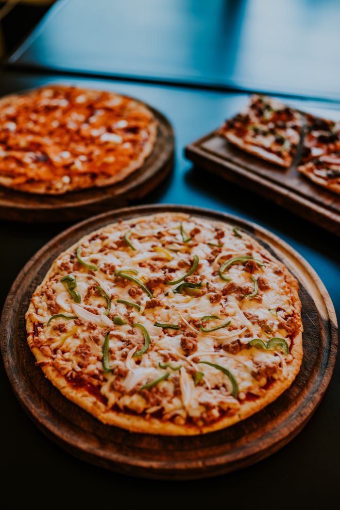 A mouthwatering display of freshly baked pizzas with various toppings on wooden trays.